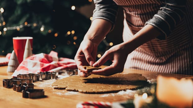 Merry Christmas, Happy New Year. Gingerbread cookies cooking, baking. Young woman sculpts, cuts and carves gingerbread cookie figures from kneaded dough using special kitchen forms. High quality photo