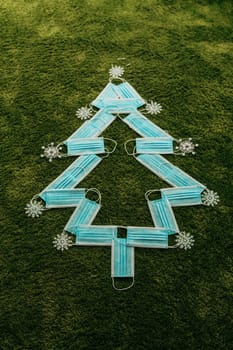 Christmas Tree Made of Blue Medical Masks on a Green Background