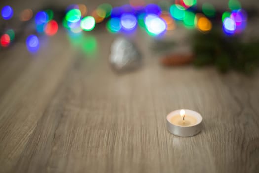 Christmas Composition of Candle on a Wooden Background With colored Light Boken