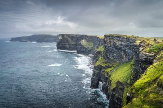 Group of people or tourists hiking and sightseeing iconic Cliffs of Moher, popular tourist attraction, Wild Atlantic Way, County Clare, Ireland