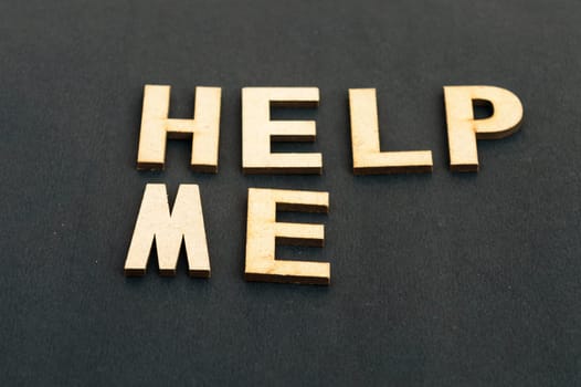 Help me symbol. Wooden cubes words help me isolated on black background, copy space. Business, motivational and help me concept.