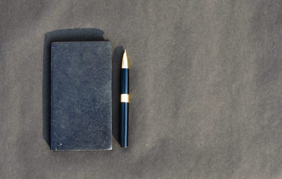 Pen placed on notebook on black background. High angle view. Copy space room for text.