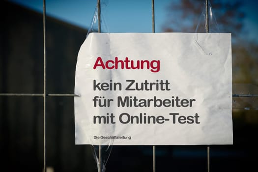 Restricting access at a fence to a company site in Germany during the Corona Pandemic. Translation: Attention, no access for employees with online test