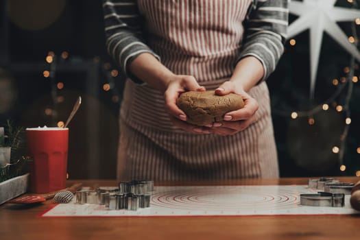 Merry Christmas, Happy New Year. Gingerbread cooking, cake, biscuit or strudel baking. Woman in apron is kneading dough. Girl gently holding, creases, cook and bake. Christmas decorations at kitchen