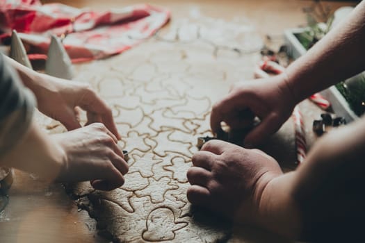 Merry Christmas, Happy New Year. Gingerbread cooking, baking. Mom and daughter make cookies, cut out different shapes of cookies using cutting metal mold on wooden table at kitchen. High quality photo