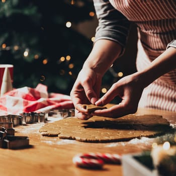 Merry Christmas, Happy New Year. Gingerbread cookies cooking, baking. Young woman sculpts, cuts and carves gingerbread cookie figures from kneaded dough using special kitchen forms. High quality photo