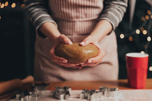 Merry Christmas, Happy New Year. Gingerbread cooking, cake, biscuit or strudel baking. Woman in apron is kneading dough. Girl gently holding, creases, cook and bake. Christmas decorations at kitchen