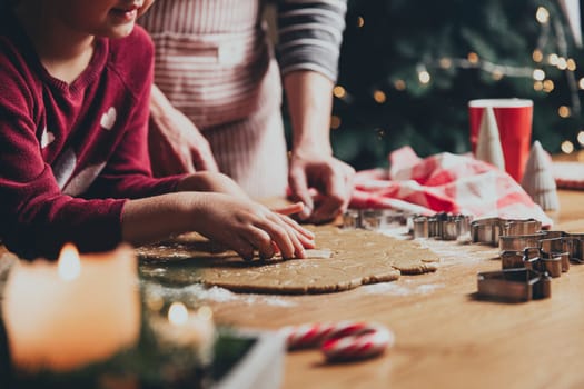 Merry Christmas, Happy New Year. Gingerbread cooking, baking. Mom and daughter make cookies, cut out different shapes of cookies using cutting metal mold on wooden table at kitchen. High quality photo