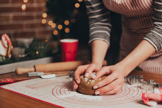Merry Christmas, Happy New Year. Gingerbread cooking, cake, biscuit or strudel baking. Woman in apron is kneading dough. Girl gently holding, creases, cook and bake. Christmas decorations at kitchen
