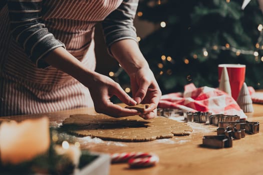 Merry Christmas, Happy New Year. Gingerbread cookies cooking, baking. Young woman sculpts, cuts and carves gingerbread cookie figures from kneaded dough using special kitchen forms. High quality photo