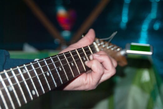 A man plays a white electric guitar
