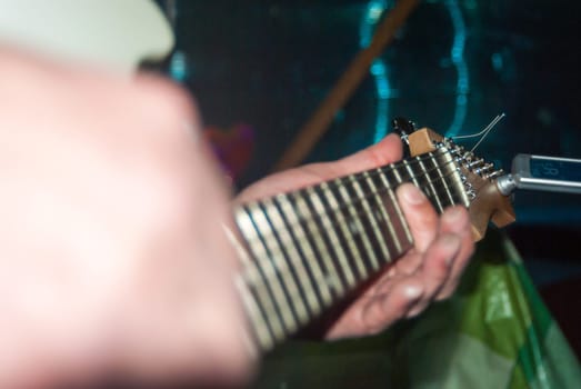 A man plays a white electric guitar