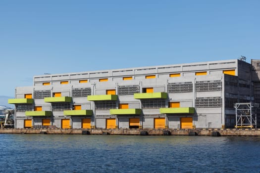 Warehouse with colorful doors and balconies at empty dock.