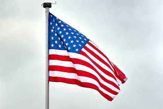 The USA flag is hanging on the flagpole. High quality photo