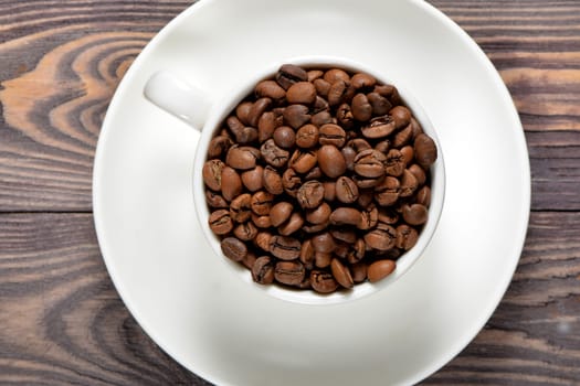 A white coffee mug filled with fragrant coffee beans stands on an old tree. High quality photo