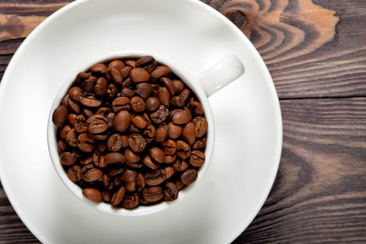 A white coffee mug filled with fragrant coffee beans stands on an old tree. High quality photo