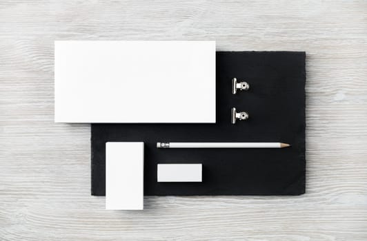 Blank stationery set. Envelope, business card, pencil, eraser and clips on stone board. Flat lay.