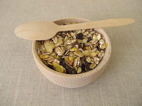 Fruit muesli with whole grain flakes and dried fruits in a wooden bowl