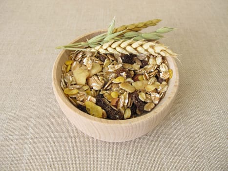 Fruit muesli with whole grain flakes and dried fruits in a wooden bowl