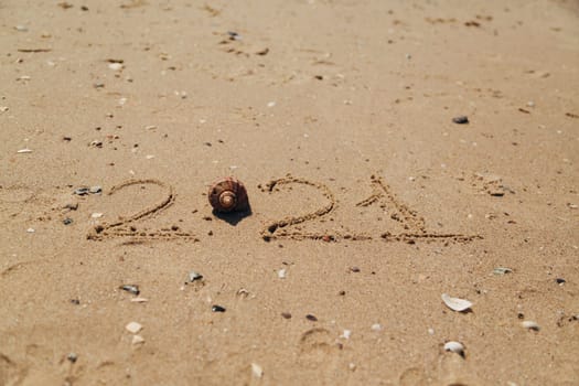 Word 2021 Written on the Sand of a Beach. New Year 2021 text on the sea beach. Vacation relax