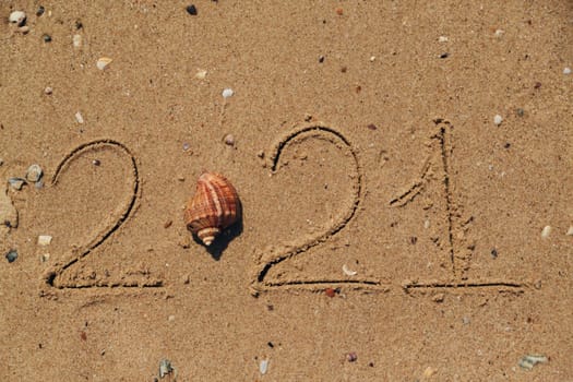 Word 2021 Written on the Sand of a Beach. New Year 2021 text on the sea beach. Vacation relax