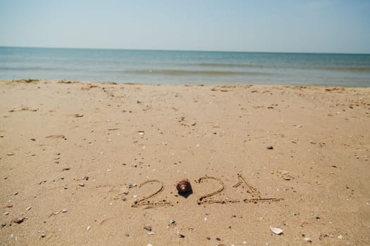 Text 2021 Written on the Sand of a Beach. Sea on a Background of Letters