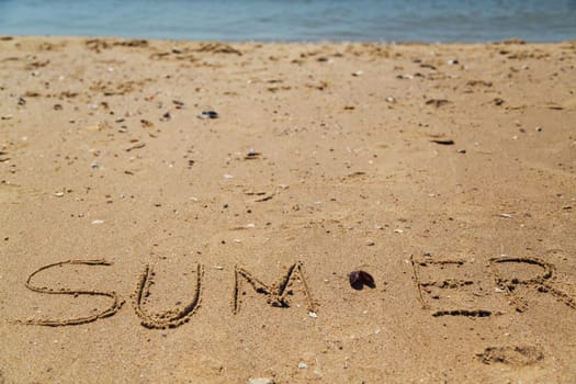 Text Summer Written on the Sand of a Beach. Sea on a Background of Letters