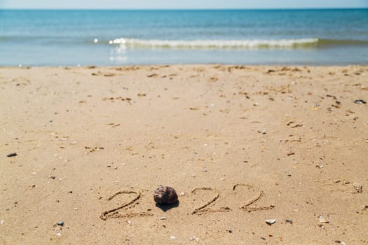 Text 2022 Written on the Sand of a Beach. Sea on a Background of Letters