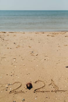 Text 2021 Written on the Sand of a Beach. Sea on a Background of Letters