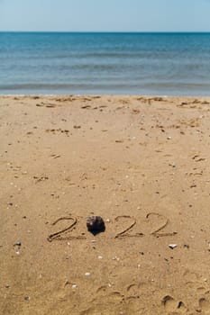 Text 2022 Written on the Sand of a Beach. Sea on a Background of Letters