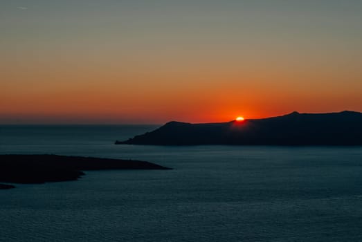 The sun at sunset almost disappeared behind the island, Santorini, Greece.