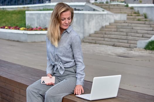 A woman with a laptop sits on a wooden platform, works online. High quality photo