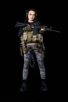 Young woman stands with a rifle on a black background. High quality photo
