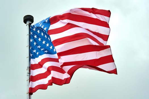 The USA flag is hanging on the flagpole. High quality photo