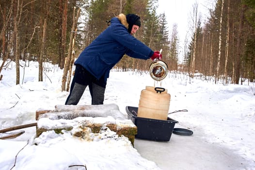 A man draws water from a spring in a plastic barrel in winter. High quality photo
