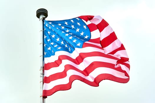 The USA flag is hanging on the flagpole. High quality photo
