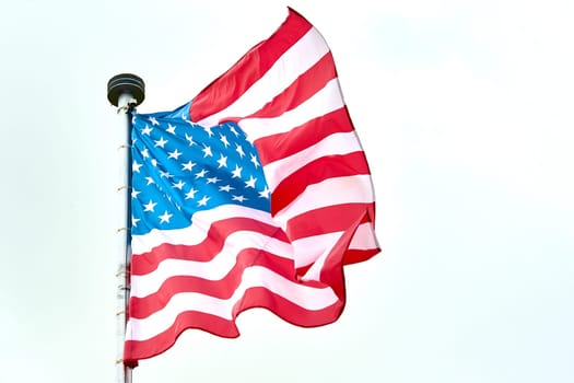 The USA flag is hanging on the flagpole. High quality photo