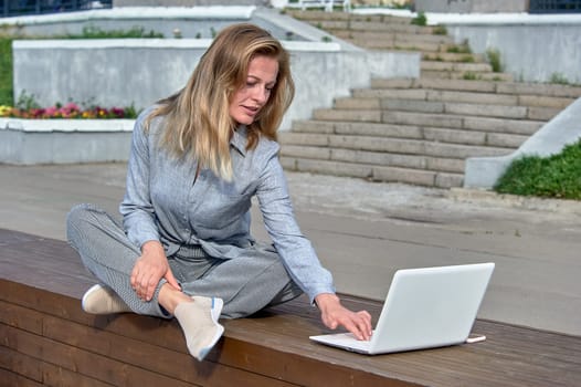 A woman with a laptop sits on a wooden platform, works online. High quality photo