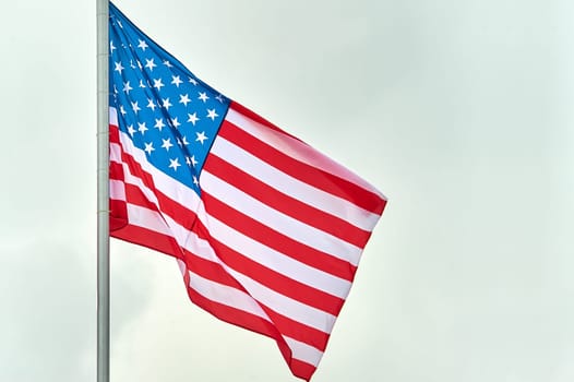 The USA flag is hanging on the flagpole. High quality photo