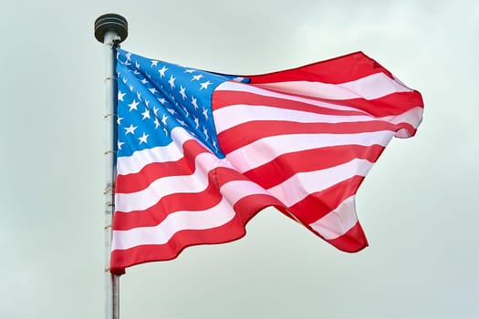 The USA flag is hanging on the flagpole. High quality photo