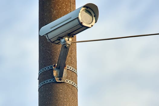 A security camera is hanging on a concrete post. High quality photo