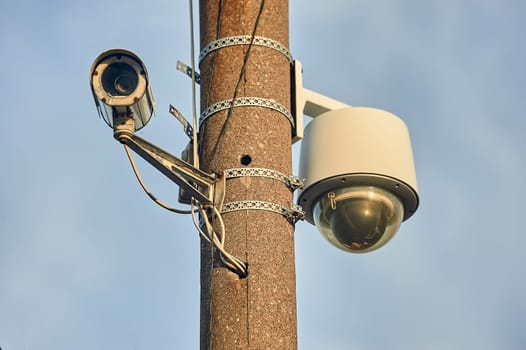 A security camera is hanging on a concrete post. High quality photo