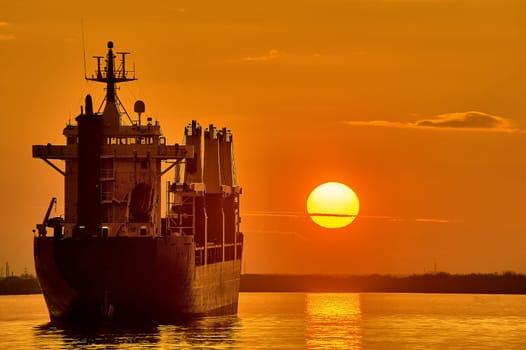 The ship is standing in the roadstead against the background of sunset. High quality photo