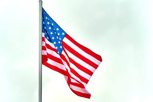 The USA flag is hanging on the flagpole. High quality photo