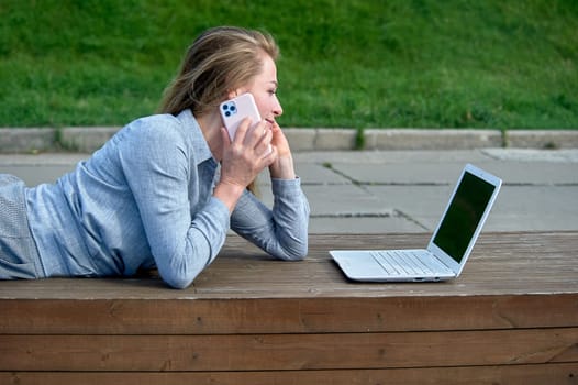 A woman with a laptop sits on a wooden platform, works online. High quality photo