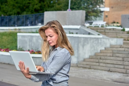 A woman with a laptop sits on a wooden platform, works online. High quality photo