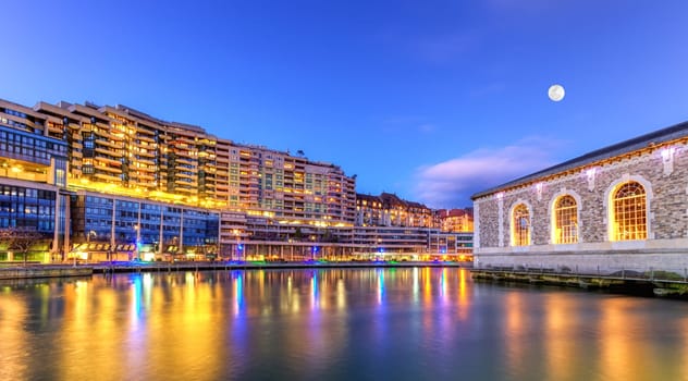 BFM buildings and Rhone river by night with full moon, Geneva, Switzerland, HDR