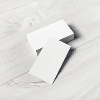 Blank white business cards on light wooden background. Mockup for ID. Template for graphic designers portfolios.
