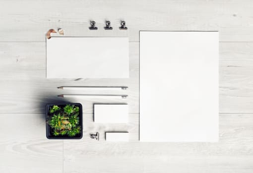 Photo of blank stationery set on light wooden background. Corporate identity template. Responsive design mockup. Top view. Flat lay.