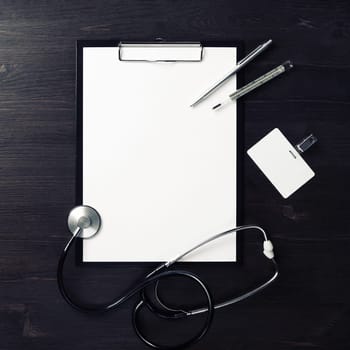 Medical still life. Blank clipboard, stethoscope, thermometer, pen and badge on wooden background. Top view. Flat lay.